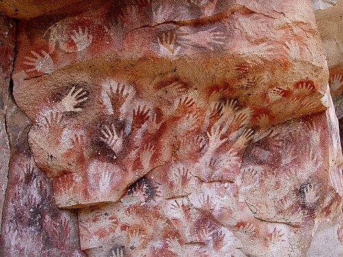 Hands at the Cuevas de las Manos upon Río Pinturas, near the town of Perito Moreno in Santa Cruz Province, Argentina. From Wikimedia By Mariano